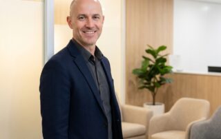 Confident man with shaved head in a professional scalp micropigmentation medical clinic setting