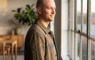 Confident man with shaved head in warm light, representing scalp micropigmentation longevity and lasting results.