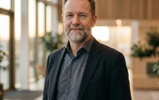 Confident man in his 50s with full healthy hair smiling — ideal hair transplant candidate for senior men