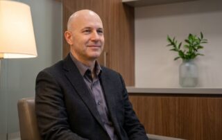 Confident man in a modern medical consultation room, representing informed scalp micropigmentation practitioner selection